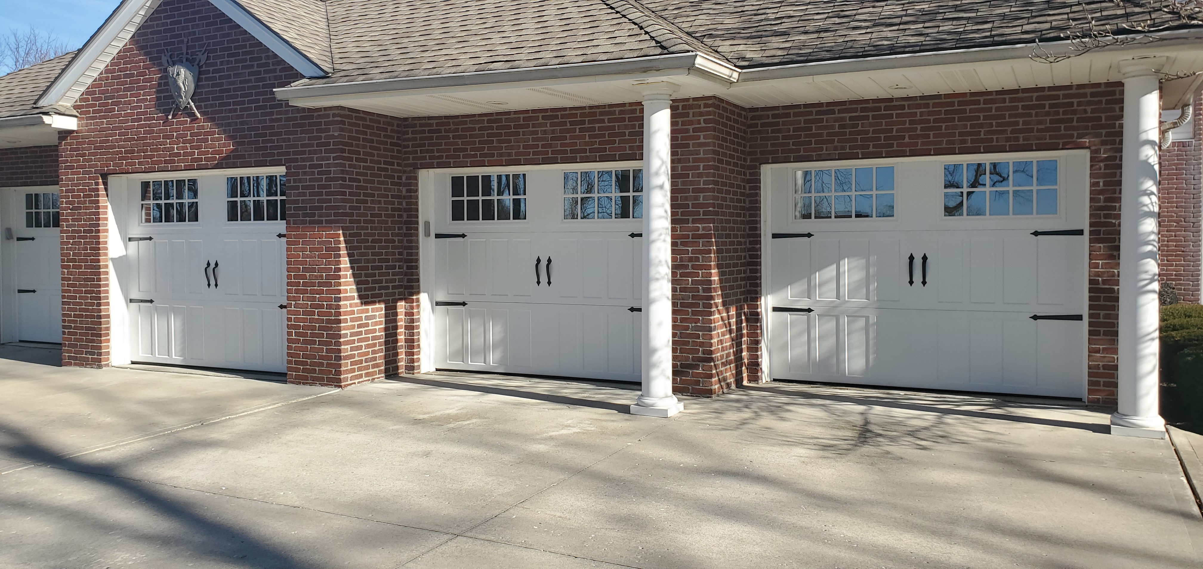 Three white carriage-house garage doors installed on a brick home in Blue Springs, Missouri