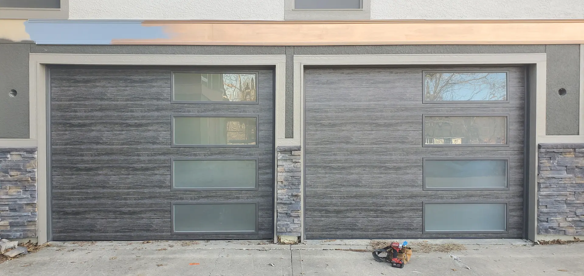 A modern dark-panelled residential garage door at dusk on a Kansas City home