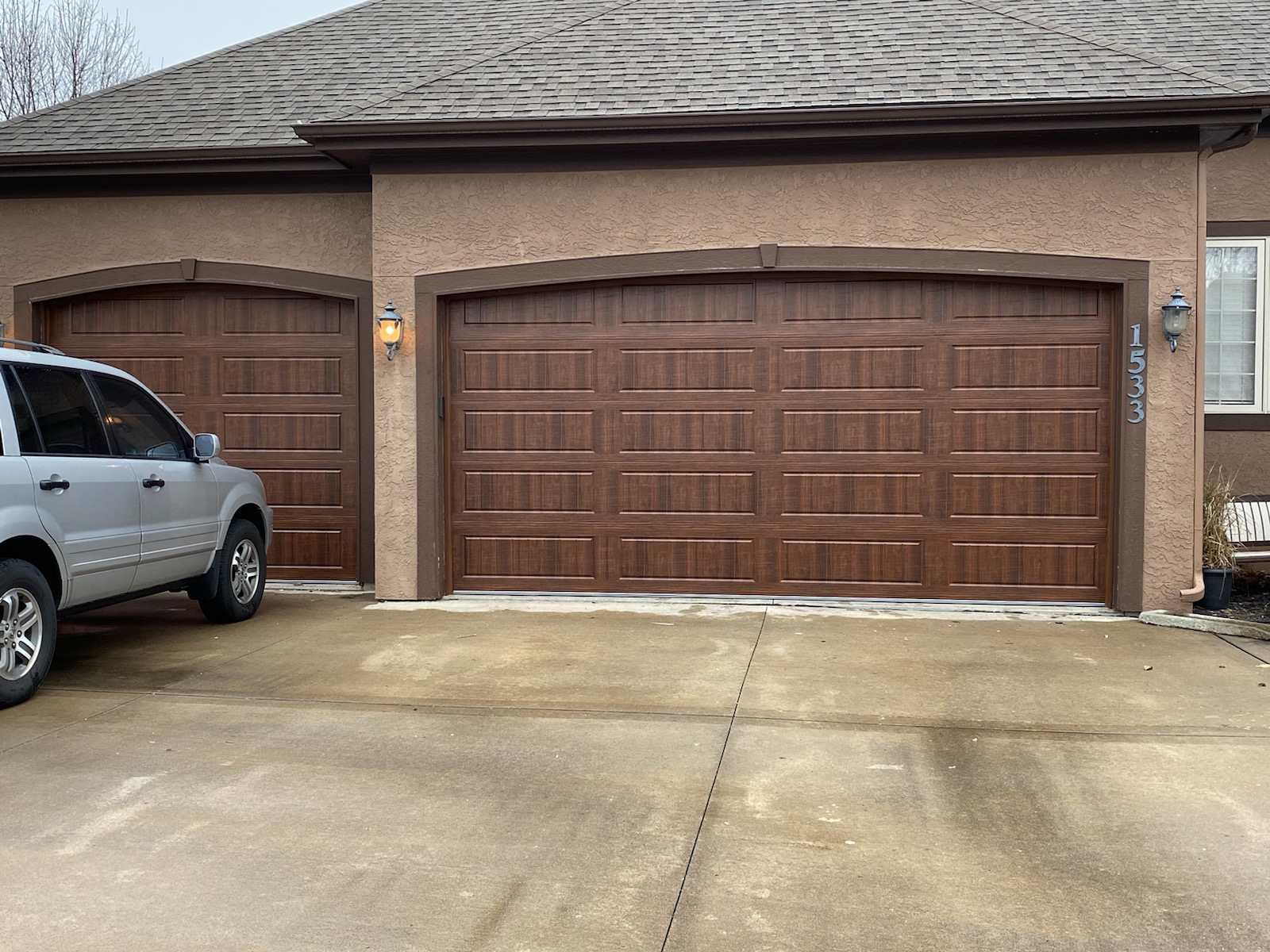 Dark walnut finish garage doors on stucco home in Grain Valley, MO